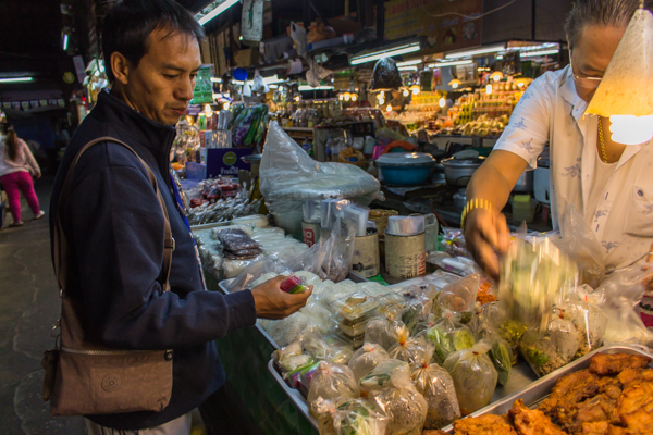 James in the market choosing which foods to give the monks. 